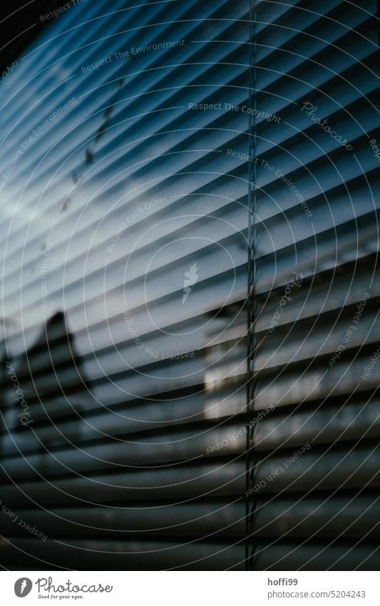 Spiegelung eines Bürohauses in einer Fensterscheibe vor geschlossener Jalousie Glas Sichtschutz Schatten Rollladen Licht Rollo grau trist Linie