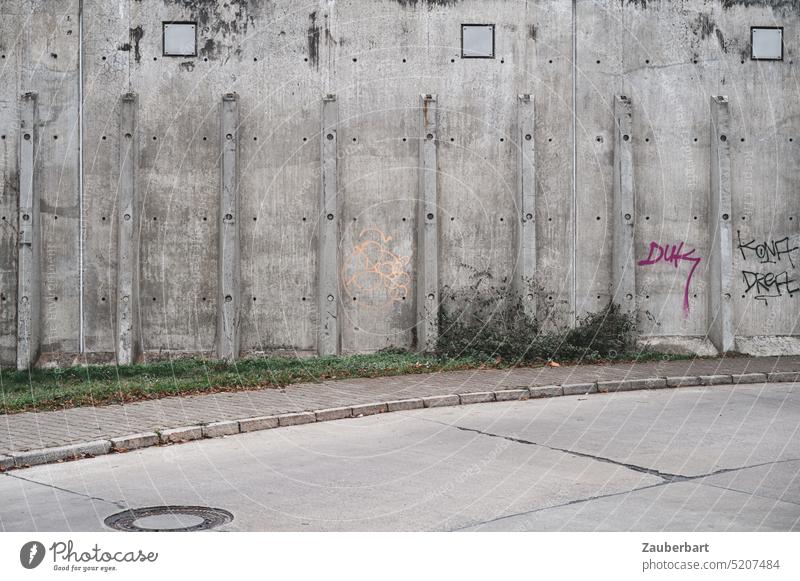 Straße aus Betonplatten schwingt sich in elegantem Bogen vor Betonwand mit Stützpfeilern, urbanes Arrangement in lichtgrau Kurve Wand städtisch Pfeiler Platten