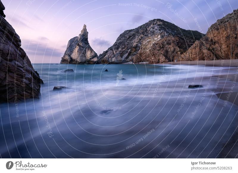 Epischer Strand Ursa, Sintra, Portugal. Strand mit Wellen und zerklüfteten Felsgipfeln im abendlichen, weichen Sonnenuntergangslicht. Atlantischer Ozean Küste Landschaft