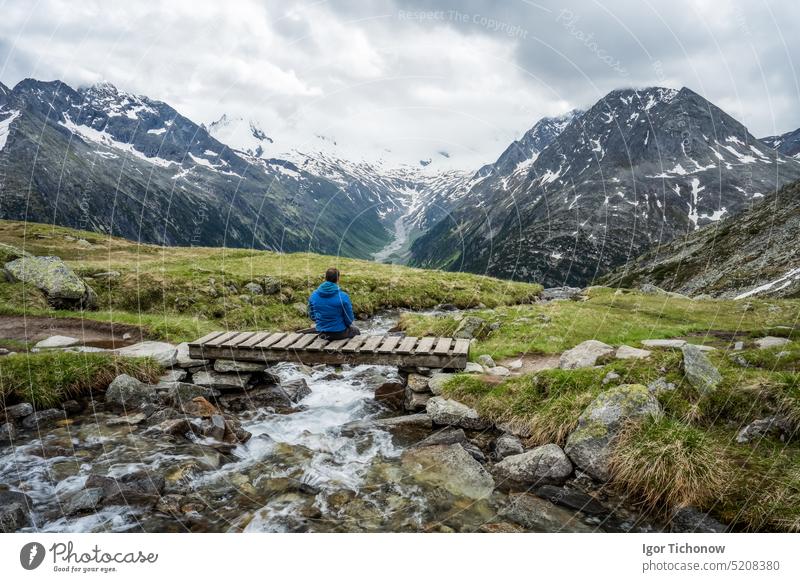 Wanderer rastet auf einer kleinen Brücke über einen Gebirgsfluss am Schlegeis See, Zillertaler Alpen, Österreich schlegeis stausee Ansicht schön wandern tirol