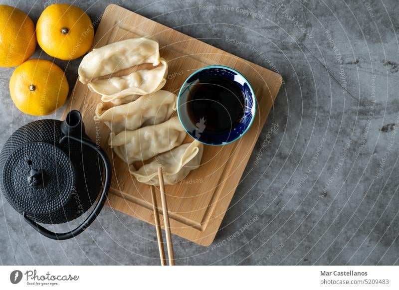 Asiatisches Essen. Dim Sum mit Sojasauce auf einem mit Orangen und Teekanne dekorierten Bambusbrett. Platz zum Kopieren. Asiatische Küche Lebensmittel Asien