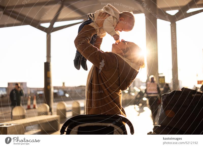 Motherat glücklich hält und hebt seinen Säugling Junge Kind in der Luft, nachdem er vor dem Flughafen-Terminal Station rejunited. Baby-Reise-Konzept. reisen