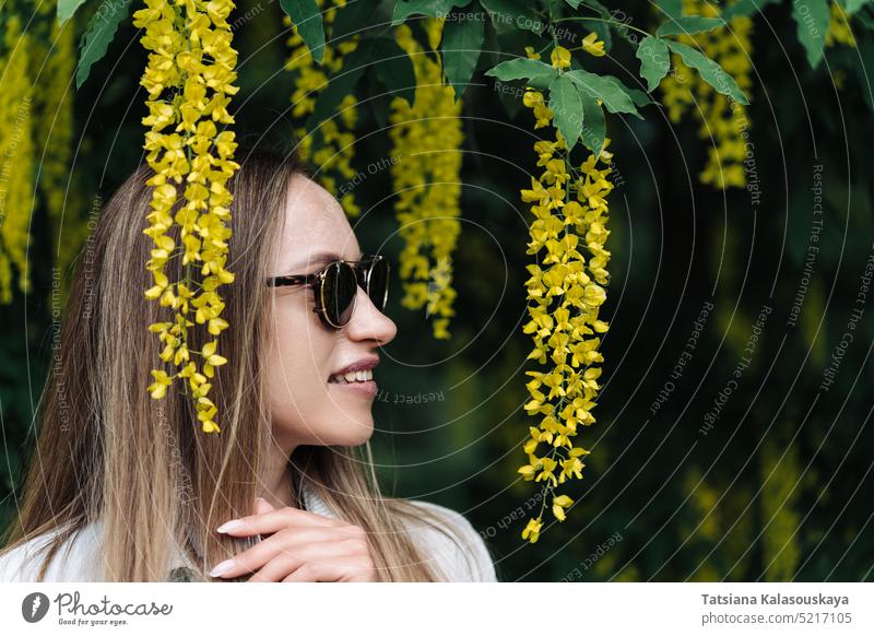 Eine Frau spaziert zwischen den blühenden gelben Blüten von Laburnum anagyroides Sommer Menschen Person Blumen Erwachsener eine Blütezeit allein Überstrahlung
