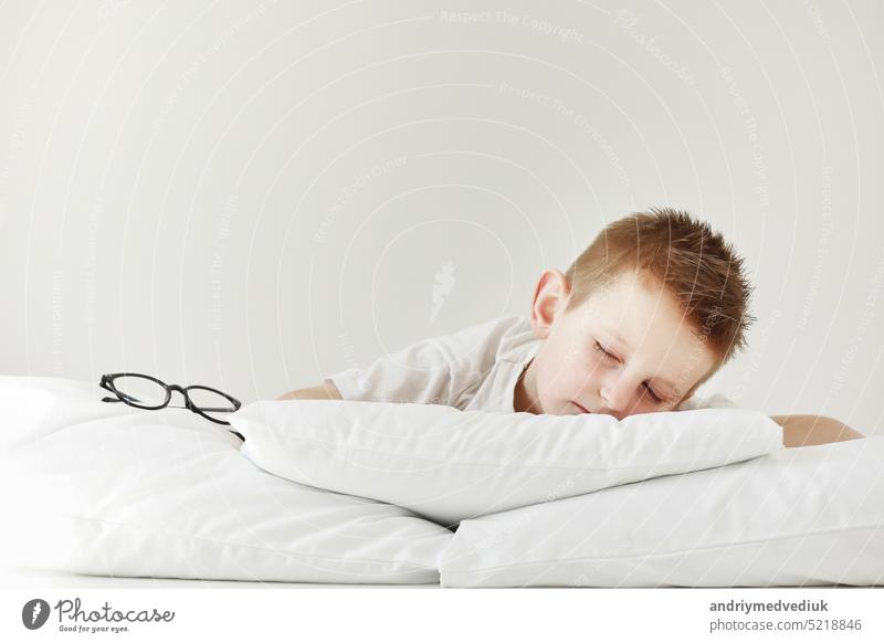 Adorable kleiner Junge im Bett schlafen. Morgen träumen auf weißem Bett. Brille von der Seite Kind Baby Kopfkissen Schlafenszeit Hand Person Gesicht Tier