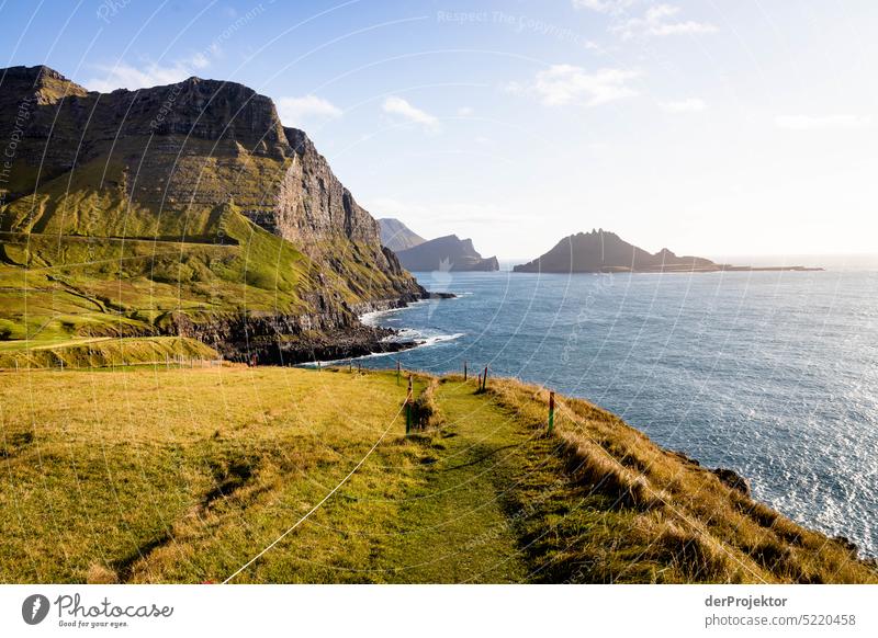 Blick auf vorgelagerte Insel und Weg im Sonnenlicht Straße felsig schlechtes Wetter Umwelt Hügel Felsen Hochland ländlich Harmonie malerisch Färöer-Inseln