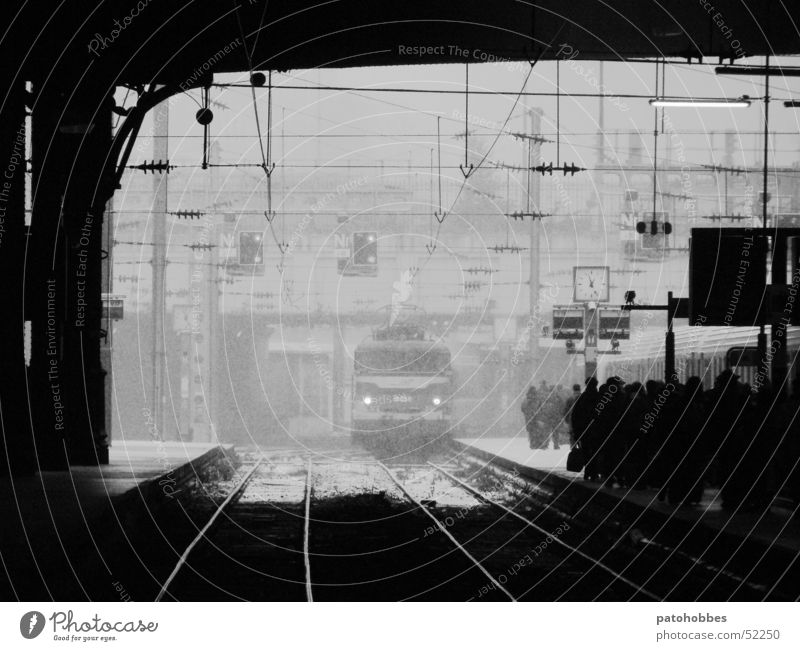 Gare St-Lazare dunkel kalt Paris Verkehr Pendler Eisenbahn Einfahrt Zugeinfahrt kommen Ankunft Fahrzeug Gleise glänzend Bahnsteig Bahnhofsuhr Zeit Schneefall