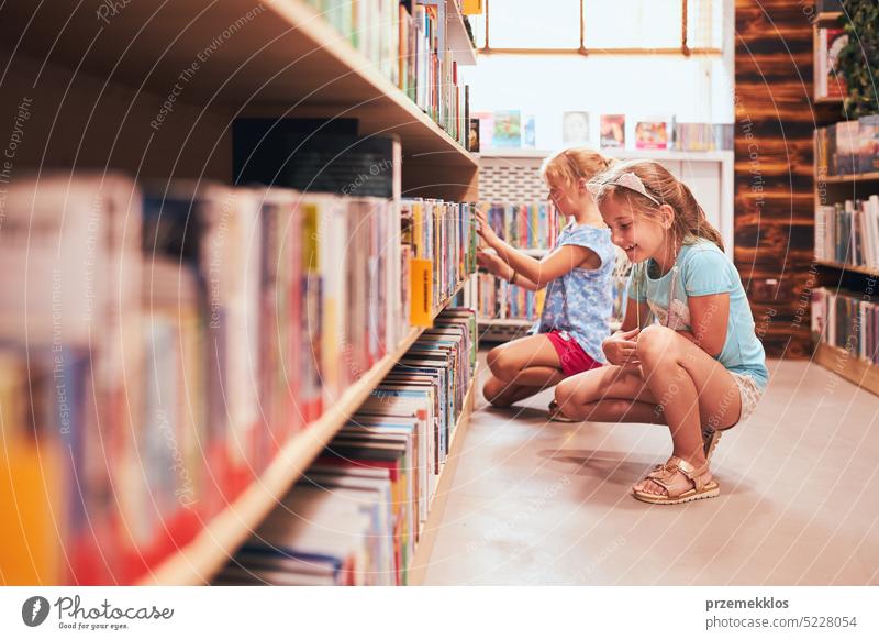 Zwei Schülerinnen wählen in der Schulbibliothek Bücher aus. Grundschüler, die aus Büchern lernen. Kinder haben Spaß im Schulclub. Zurück zur Schule Rücken