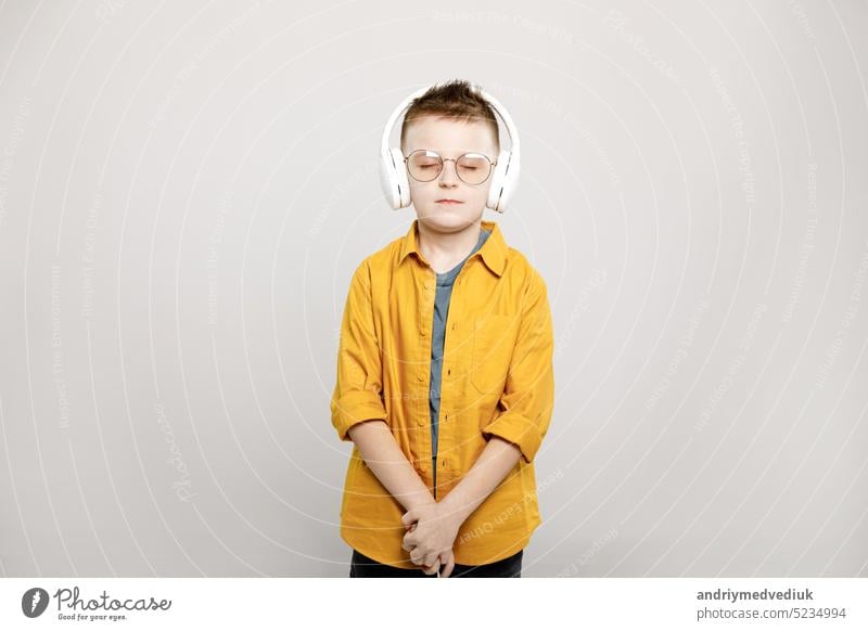liebenswertes Kind Junge in weißen Kopfhörer und Brille isoliert auf grauem Hintergrund lässig Kindheit niedlich Spaß Glück Freude Musik Person Porträt Mode