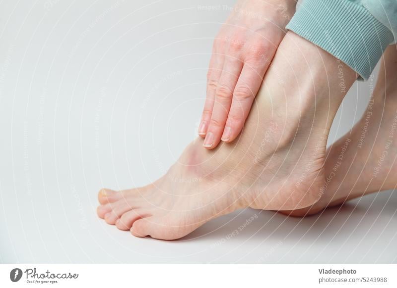 Frau tragen Salbe auf Knöchel mit Prellung und Schwellung auf ihrem Fuß auf weißem Hintergrund blaue Flecken Fußknöchel Bein Verletzung Versetzung Blutergüsse