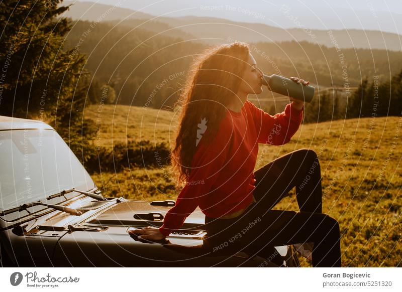 Junge Frau entspannt sich auf der Motorhaube eines Geländewagens auf dem Lande Auto jung Kaukasier Feiertag Sommer Fahrzeug Ausflug PKW Urlaub Lifestyle