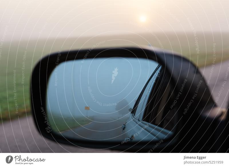 Ein Auto fährt eine Straße entlang, im Seitenspiegel spiegelt sich der  Himmel und die Straße. - ein lizenzfreies Stock Foto von Photocase