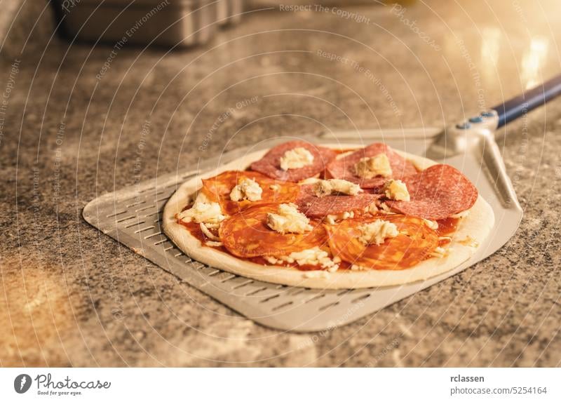Pizzabäcker bei der Zubereitung der typischen Salamipizza in einer italienischen Pizzeria vorbereiten Teigwaren roh Holzfeuer Ziegelofen Chefkoch Feinschmecker