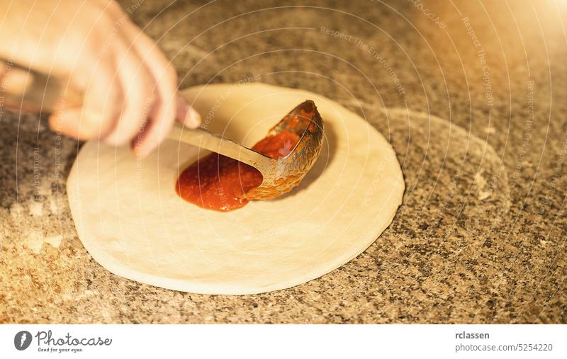 Pizzabäcker bereitet rohe Pizza mit Tomatensauce und Löffel in der italienischen Pizzeria zu vorbereiten Ketchup Hand Saucen Teigwaren Holzfeuer Ziegelofen