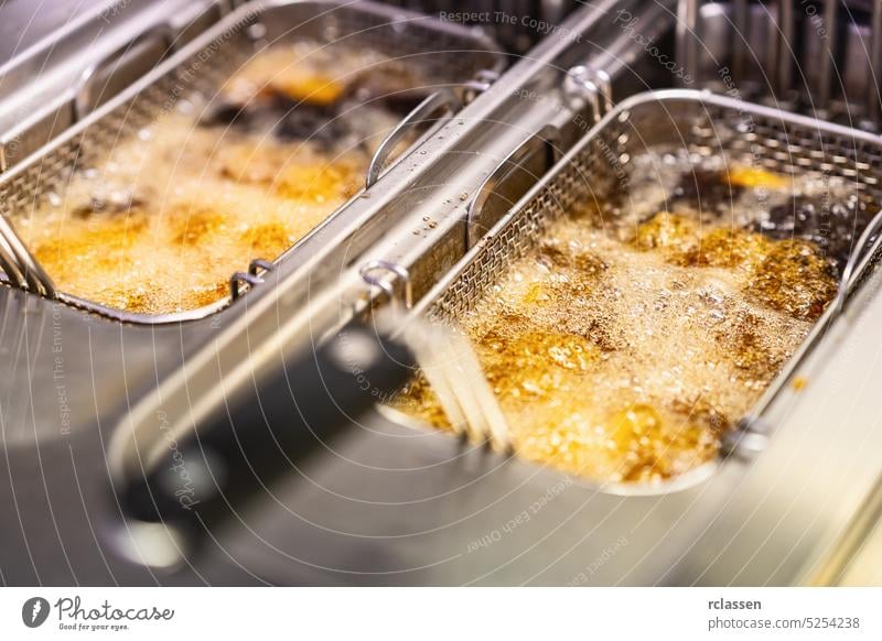 Pommes frites beim Kochen. Gitter mit Streifen Hopfenkartoffel in kochendes Öl gesenkt. Konzept von Fast Food Fritteuse braten tief Erdöl professionell
