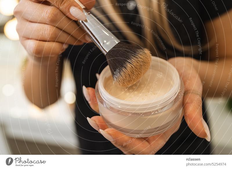 Maskenbildnerin hält Puderdose mit Pinsel zum Abpudern einer Kundin im Schönheitssalon Künstler Gesicht Kunde Freizeit Salon Dienstleistungsbranche