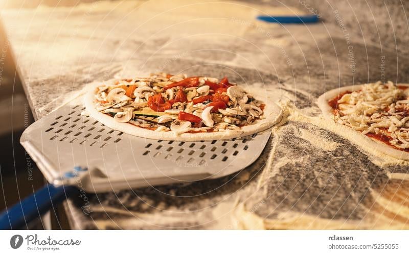 rohe italienische Frischpizza auf der Schale in der Pizzeria Teigwaren Holzfeuer Ziegelofen Chefkoch Feinschmecker professionell Arbeit traditionell Herd