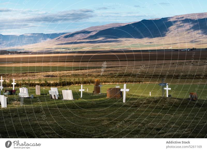 Katholischer Friedhof auf dem Lande Landschaft Grabstein grasbewachsen Tal Feld malerisch wolkig Gras Natur Island Blauer Himmel Sonnenlicht Gedenkstätte ruhig