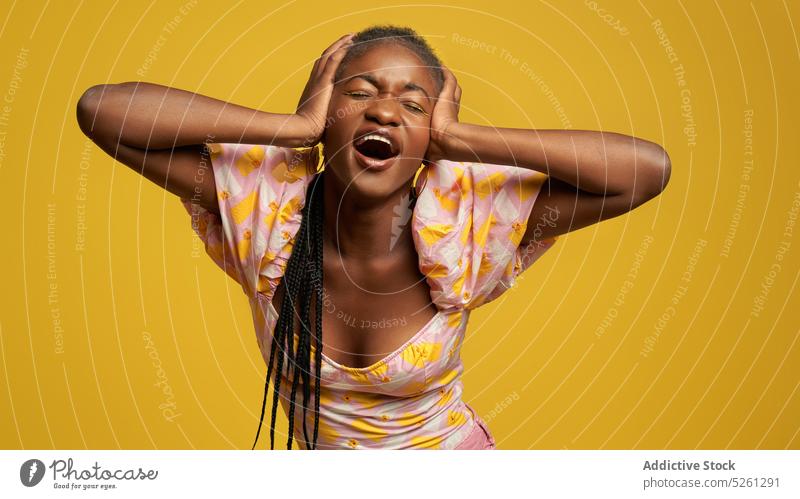 Ethnische Frau demonstriert Migräne in der Nähe der gelben Wand Tastkopf Schmerz Augen geschlossen Kleid Stil verärgert hell jung müde farbenfroh Afroamerikaner