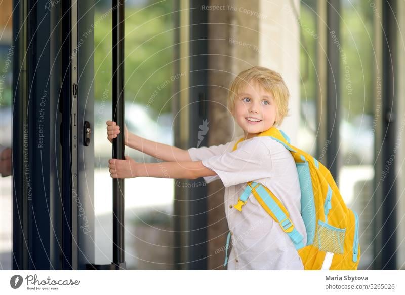 Kleiner Schuljunge verlässt das Haus, um nach den Ferien zur Schule zu gehen. Kind im Hof eines Schulhauses. Gute Bildung für Kinder. Kinder zurück in die Schule