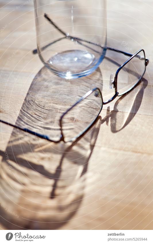 Trinkglas und Brille brille bügel ersatzbrille holz holzplatte liegen optik optiker schatten sehhilfe tisch zusammen zwei paar duo licht holztisch maserung