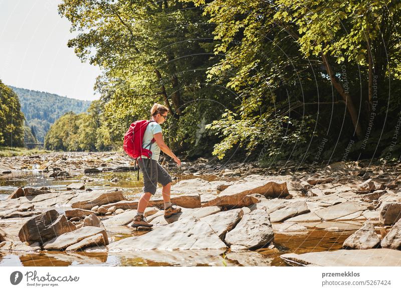 Trekking mit Rucksack Konzeptbild. Weibliche Backpacker trägt Trekking-Stiefel überqueren Berg Fluss. Frau Wandern in den Bergen während der Sommerreise
