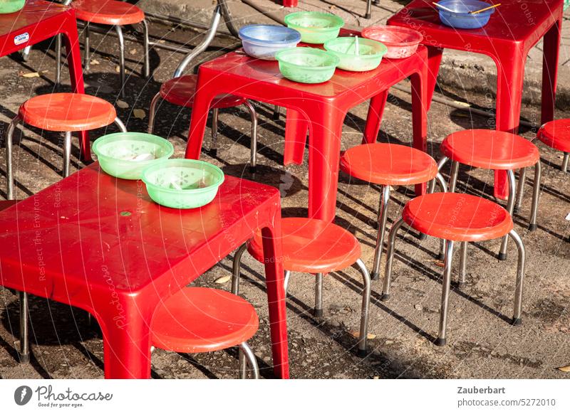 Rote Tische, rote Hocker, darauf bunte Plastikschalen, bilden eine Gruppe runder Formen Schalen sitzen Essen street food Vietnam sozial gemeinsam Kindergarten