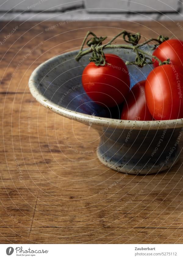 Eine handgetöpferte, glasierte Schale mit Tomaten auf dem Tisch, gesunde Ernährung töpfern Glasur blau rot Lebensmittel Gemüse frisch Gesundheit vegan