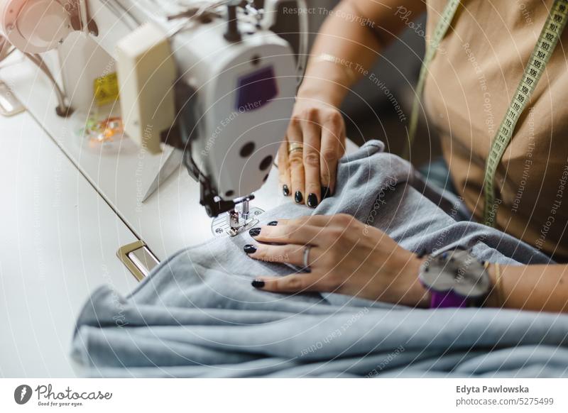 Nahaufnahme der Hände einer Frau beim Nähen an der Nähmaschine Modedesignerin Handwerk Schneidern Herstellung handgefertigt Näherin Kleinunternehmen Werkstatt