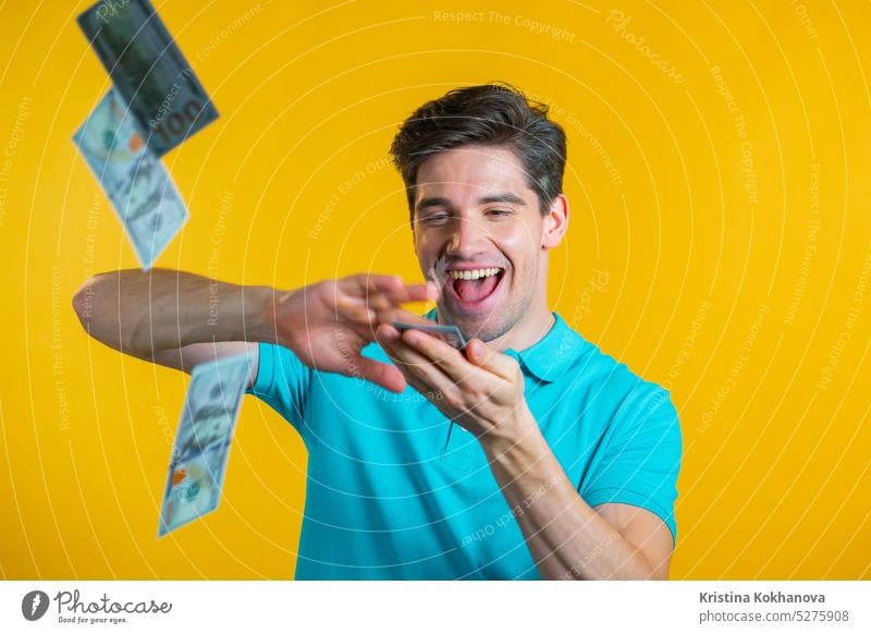 Mann mit glücklichem Gesicht verstreut Geld. Die Leute geben zu viel Geld aus. Der Mann ist bündig mit Dollar auf gelbem Studio Hintergrund. Währung Finanzen
