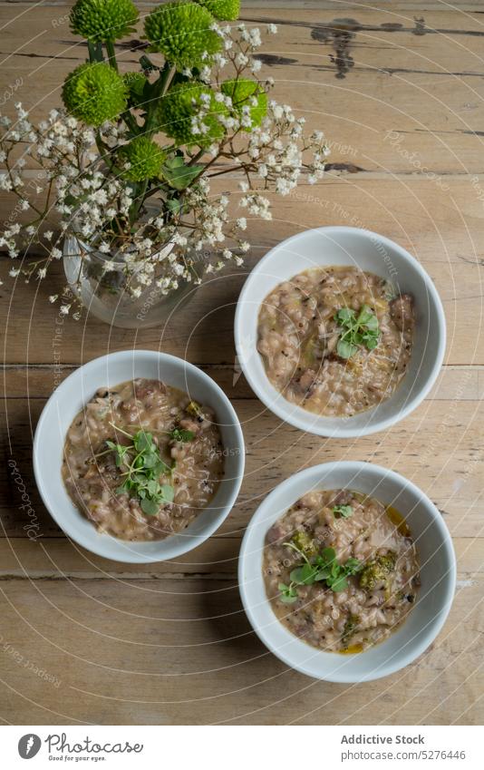 Schalen mit Brei in der Nähe blühender Blumen Frühstück Haferbrei gesunde Ernährung Mahlzeit Schalen & Schüsseln Vase Blumenstrauß Blütezeit Lebensmittel