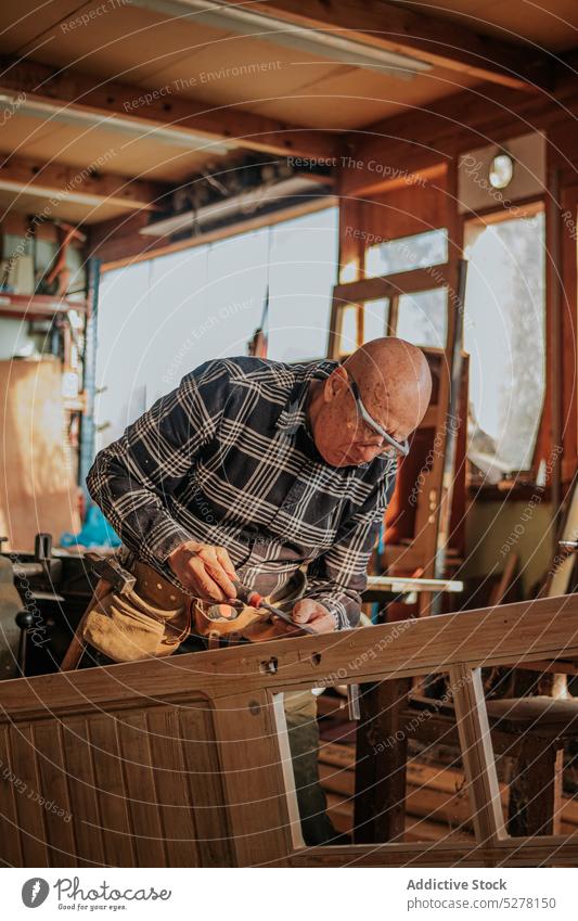 Älterer Schreiner beim Meißeln in der Werkstatt Mann Beitel Tischlerin geschnitten Kunsthandwerker Schiffsplanken Holz Fähigkeit Kunstgewerbler Schreinerei