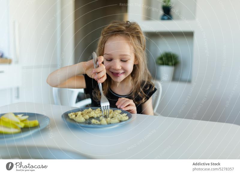 Glückliches Vorschulmädchen isst Nudeln am Tisch Mädchen Kind Ernährung nähren essen Lächeln Lebensmittel Spätzle Nährstoff Kindheit Teller Inhalt niedlich