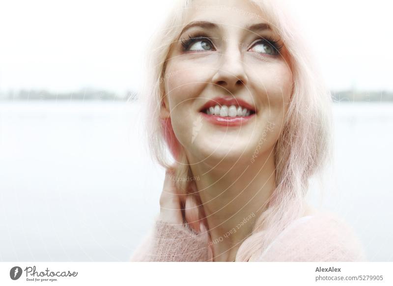 Junge Frau Mit Pink Blonden Haaren Schaut In Den Himmel Und Lächelt Vor Einem See Mit Seeufer In 2567