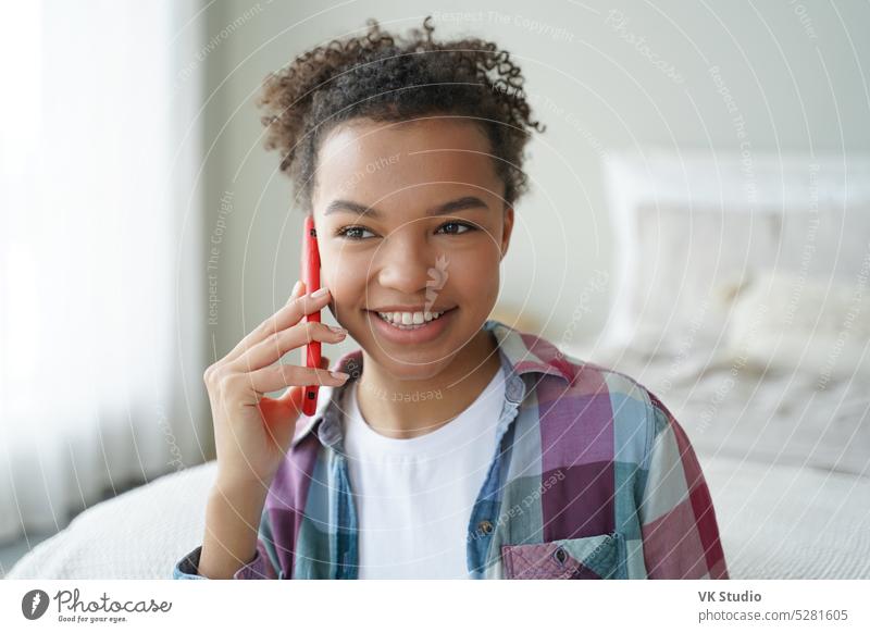 Lächelnde gemischte Rasse Teenager-Mädchen beantwortet Telefonanruf, genießt Gespräch mit Freund im Schlafzimmer zu Hause Anruf Smartphone Kommunizieren