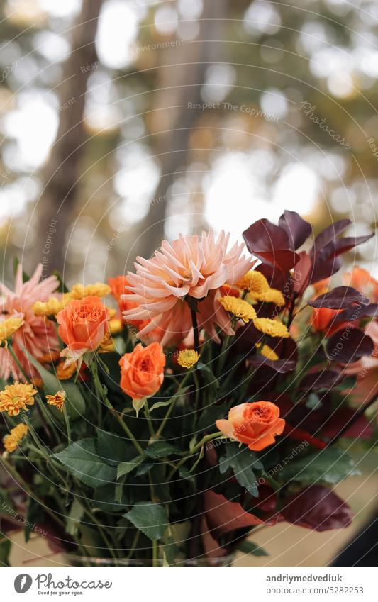 Schönes herbstliches Arrangement von Blumen in einer Glasvase im Freien. Herbststrauß mit Gartenblumen. Bunte Dahlie und Chrysantheme Geschenk für Jahrestag, Geburtstag, Muttertag.