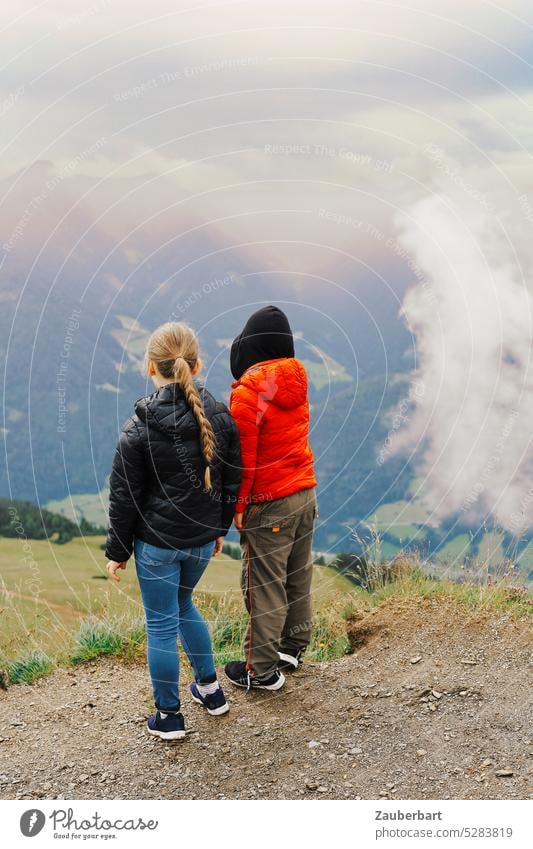 Zwei Kinder in Rückansicht stehen auf einem Berg und schauen ins Tal Paar Wolken wandern Wanderung Natur Landschaft Kindheit Glück erstaunt neugierig Abenteuer