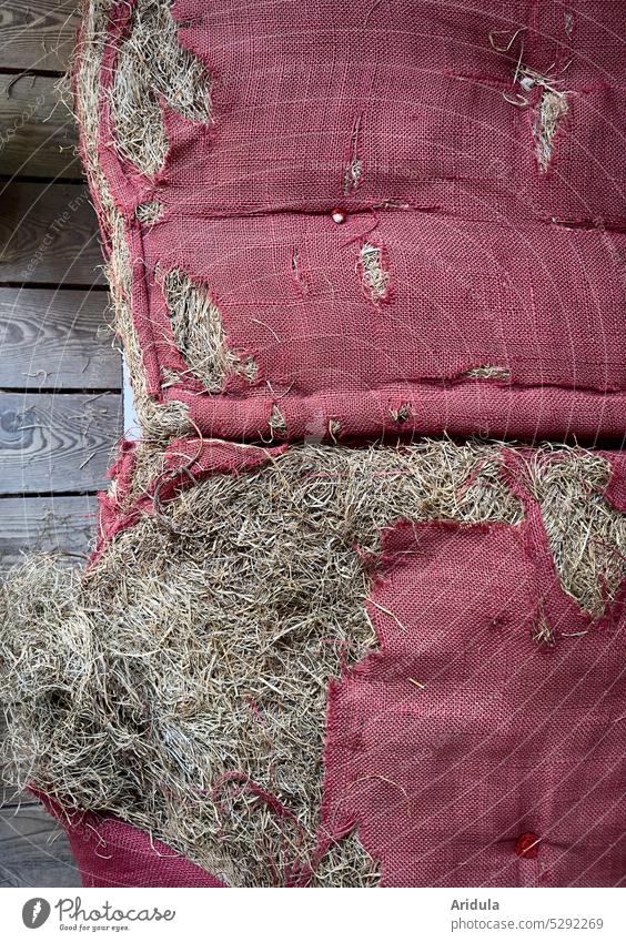 Alte zerschlissene Polster mit Heu gefüllt kaputt zerrissen Löcher Stoff rot Sitzpolster alt Holz Holzfußboden Holzbretter