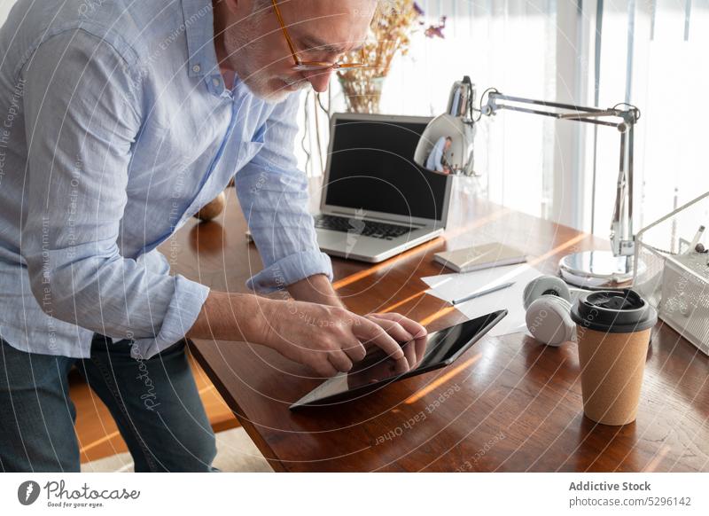 Seriöser Mann arbeitet zu Hause am Tablet Unternehmer freiberuflich benutzend digital Tablette heimwärts Büro Arbeit Business abgelegen Browsen Apparatur Gerät