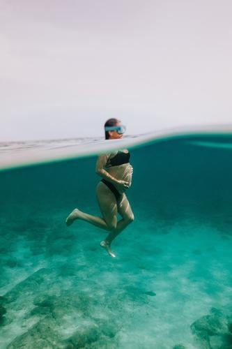 Unerkennbare schwangere Frau beim Tauchen im Meer schwimmen unter Wasser Fisch Sinkflug unterseeisch Urlaub MEER Bikini durchsichtig blau Feiertag reffen