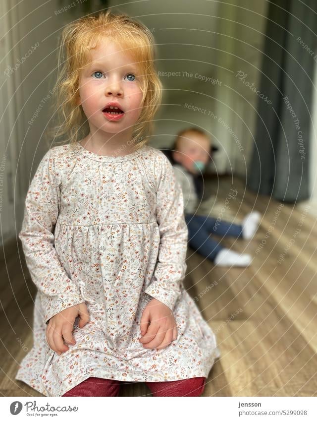 Drei Jahre altes Mädchen mit überraschtem Blick Kind Kindheit kindlich dreijährig Kleinkind Mensch niedlich unscharfer Hintergrund fußboden Farbfoto 1-3 Jahre