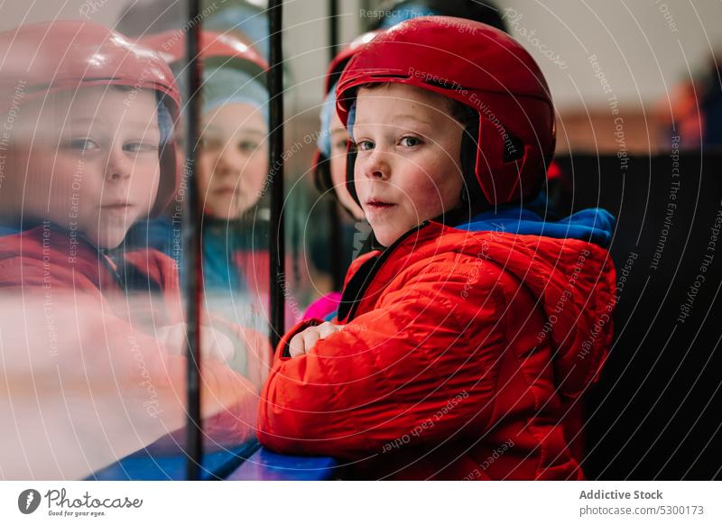 Nachdenklicher Junge mit Blick auf die Eislaufbahn Winter Kind Sicherheit nachdenklich Zaun behüten kalt besinnlich ernst Schutzhelm Saison Aktivität Sport