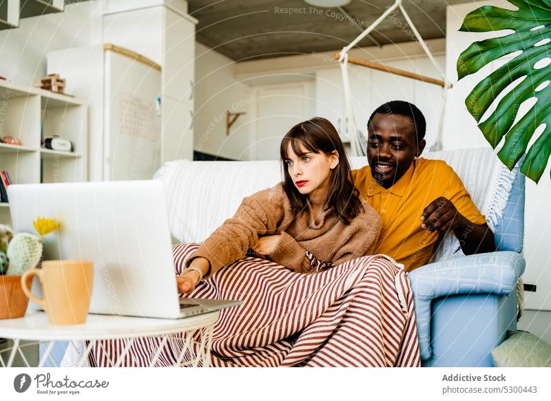 Ehepaar benutzt Laptop im Wohnzimmer zu Hause Paar benutzend Sofa Partnerschaft Browsen Zusammensein Zeit verbringen vielfältig online heimwärts