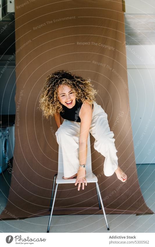 Fröhliche Frau auf einem Stuhl stehend Model Studioaufnahme sorgenfrei Lachen Spaß Vorschein expressiv Freude Spaß haben Lächeln heiter Glück positiv jung