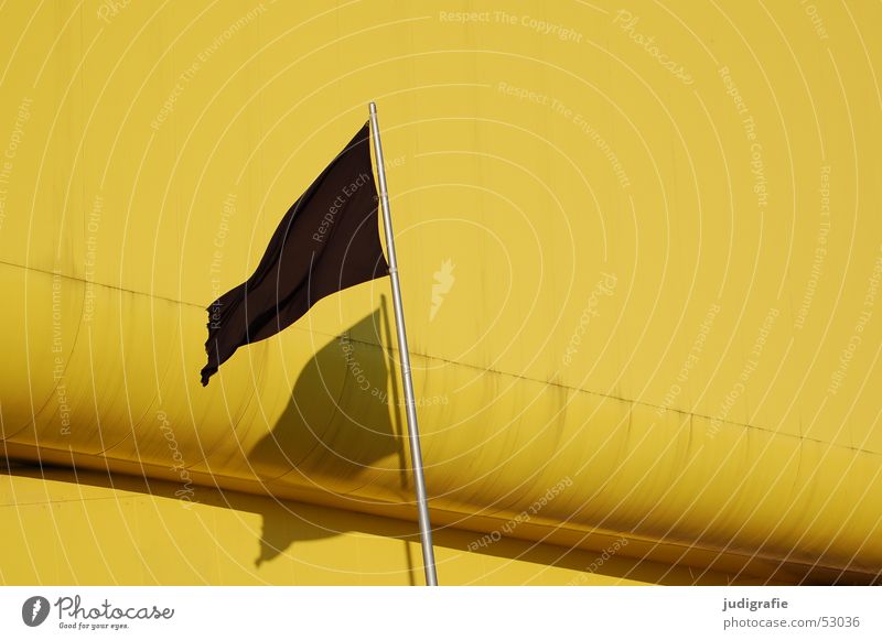 Schwarze Fahne mit Schatten vor gelbem Gebäude schwarz Licht Hannover Fahnenmast Pavillon Litauischer Pavillon modern Weltausstellung Architektur
