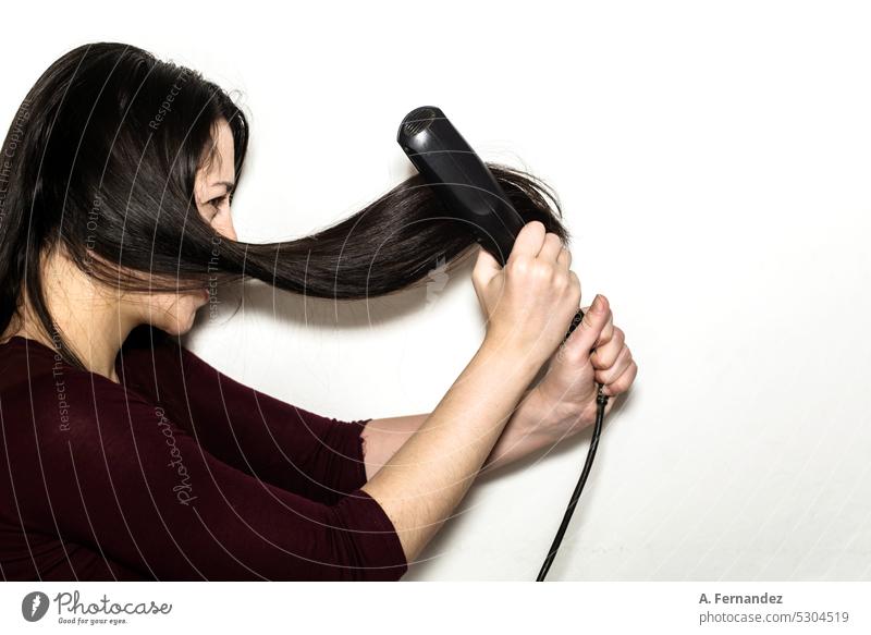 Eine Frau hält fest und wütend Haarglätter auf einem weißen Hintergrund. Konzept der Beschädigung durch fortgesetzte Verwendung von Wärme auf das Haar. glätten