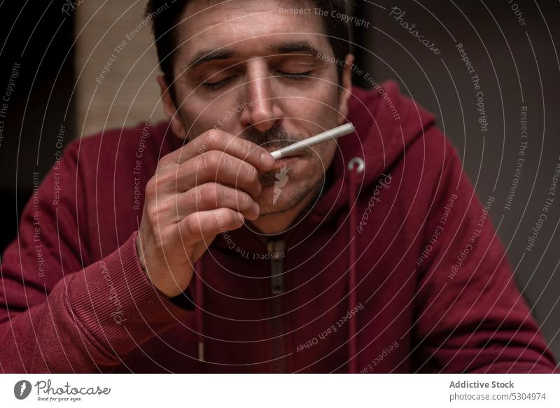 Ruhiger Mann, der mit geschlossenen Augen an einem Joint riecht riechen Cannabis Aroma Blatt sich[Akk] entspannen genießen Marihuana Augen geschlossen Rauch