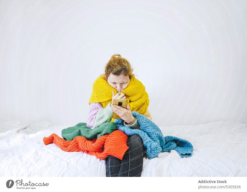 Konzentrierte Frau mit Pullover, die auf dem Bett auf ihrem Smartphone surft benutzend Nachricht Browsen Konzentration Internet Schlafzimmer Fokus Mobile