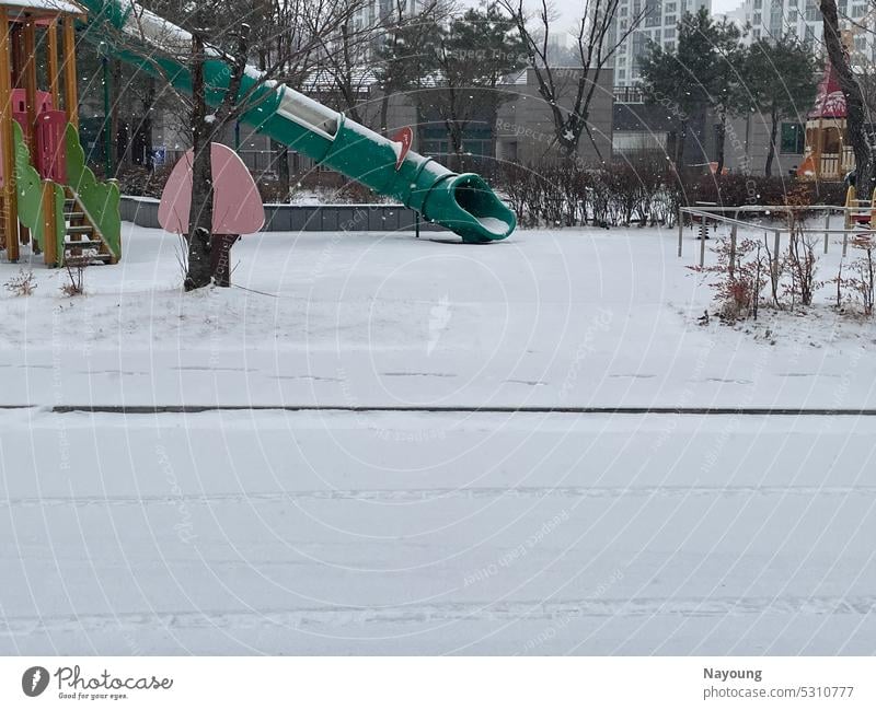 verschneite kalte Winterszene auf dem Spielplatz. Schnee Stock Großstadt Stadtbild weiß weißer Hintergrund Schneefall frieren klirrende Kälte Baum im Freien