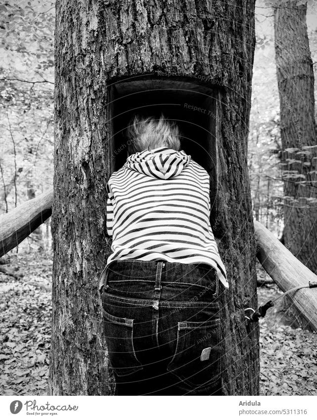 Kind steckt seinen Kopf in ein rechteckiges Baumloch s/w Kindheit Bäume Wald verstecken lauschen Baumgeräusche Baumstamm Holz hören Natur Waldbaden Erholung