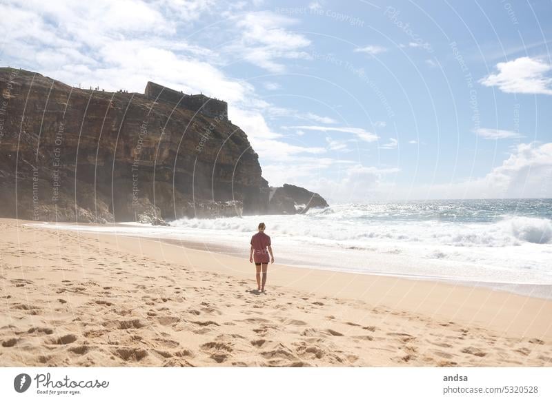 Frau am Strand geht zum Meer Kliff Wellen Sand Sandstrand Portugal Nazare Küste Schönes Wetter Wasser Außenaufnahme Natur Sommer Ferien & Urlaub & Reisen
